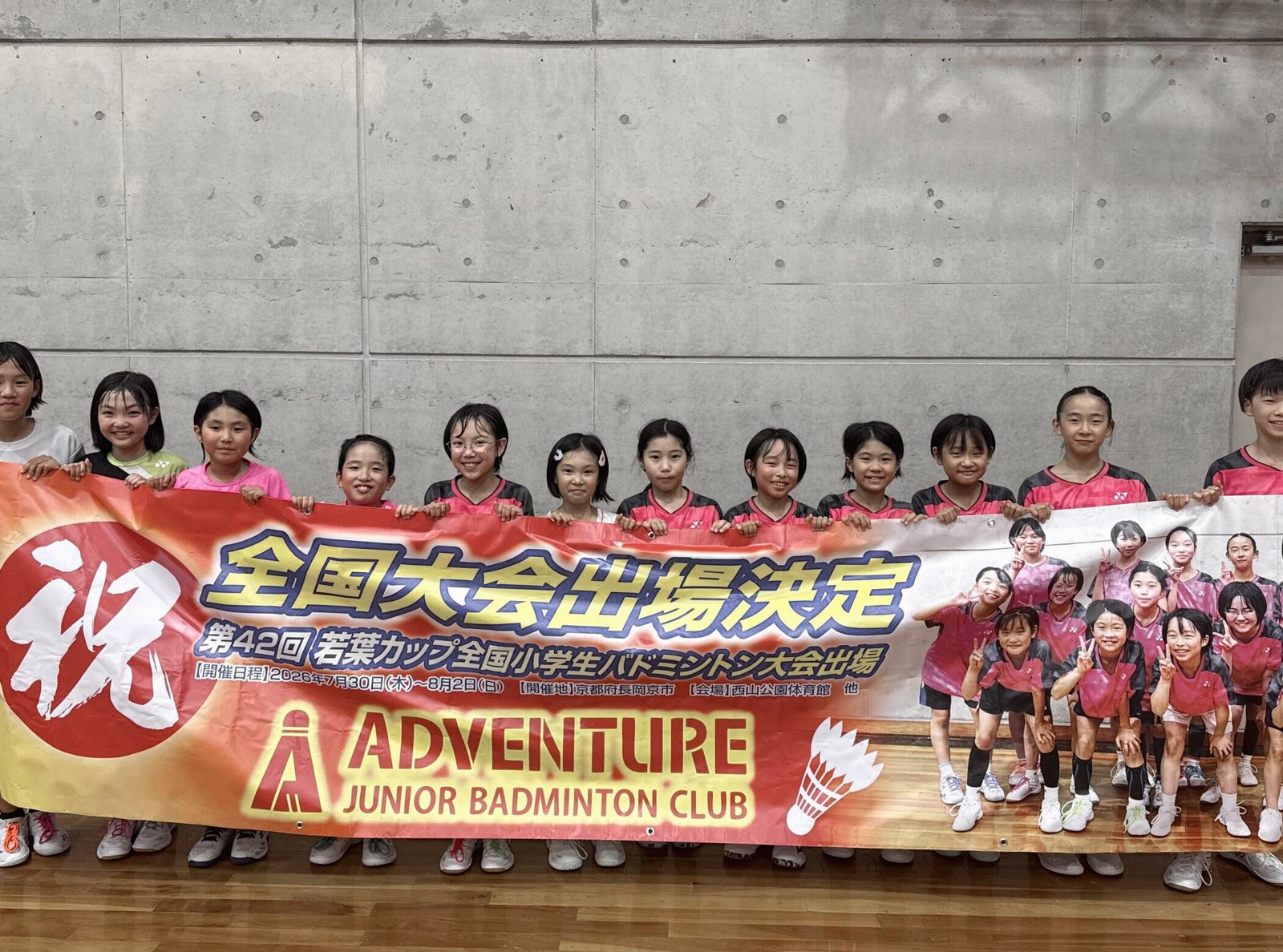 「全国大会出場決定」の横断幕を持つクラブの子どもたち