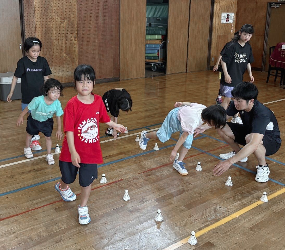 床に置いたシャトルのまわりで、コーチと動きの練習をする子どもたち
