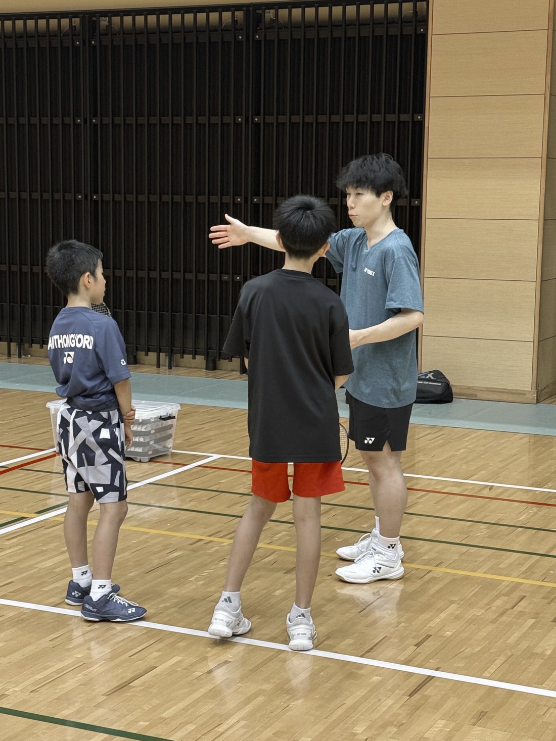 コートの上で、コーチが子どもに動きを説明している